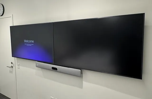 Two displays mounted side by side with a video bar underneath