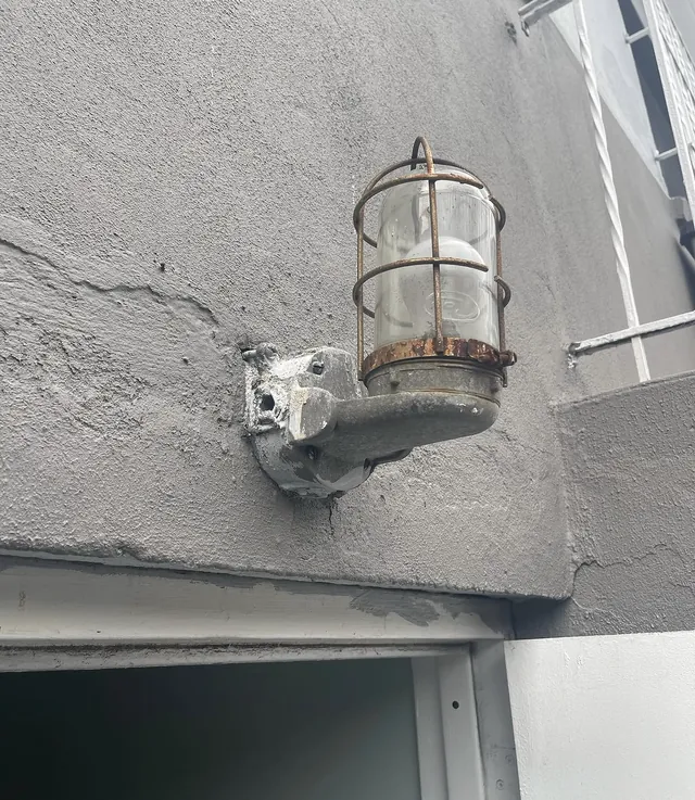 Old rusted caged outdoor light fixture before replacement