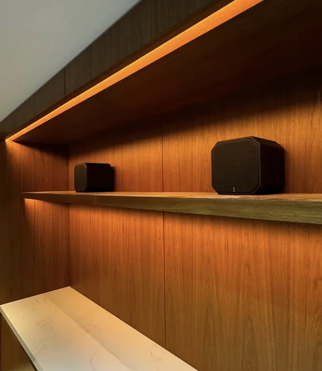 Wood shelving with warm LED strip lighting and small speakers