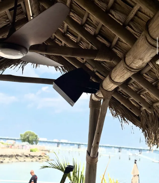 Outdoor speaker mounted under a thatched patio roof by the water