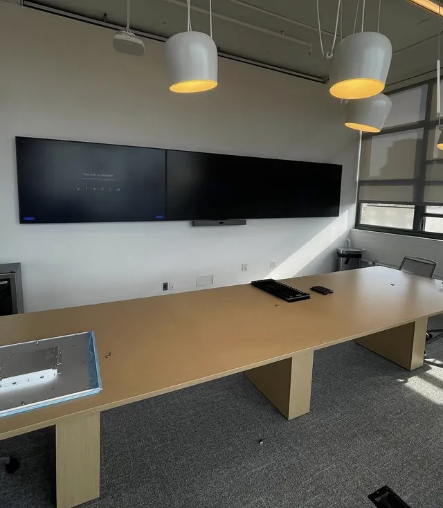 Row of 75-inch displays mounted over a long conference table